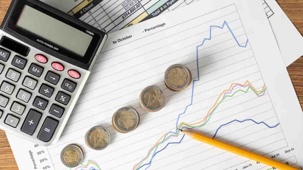 A calculator, coins, and graphs on financial documents tracking trends and percentages over time.