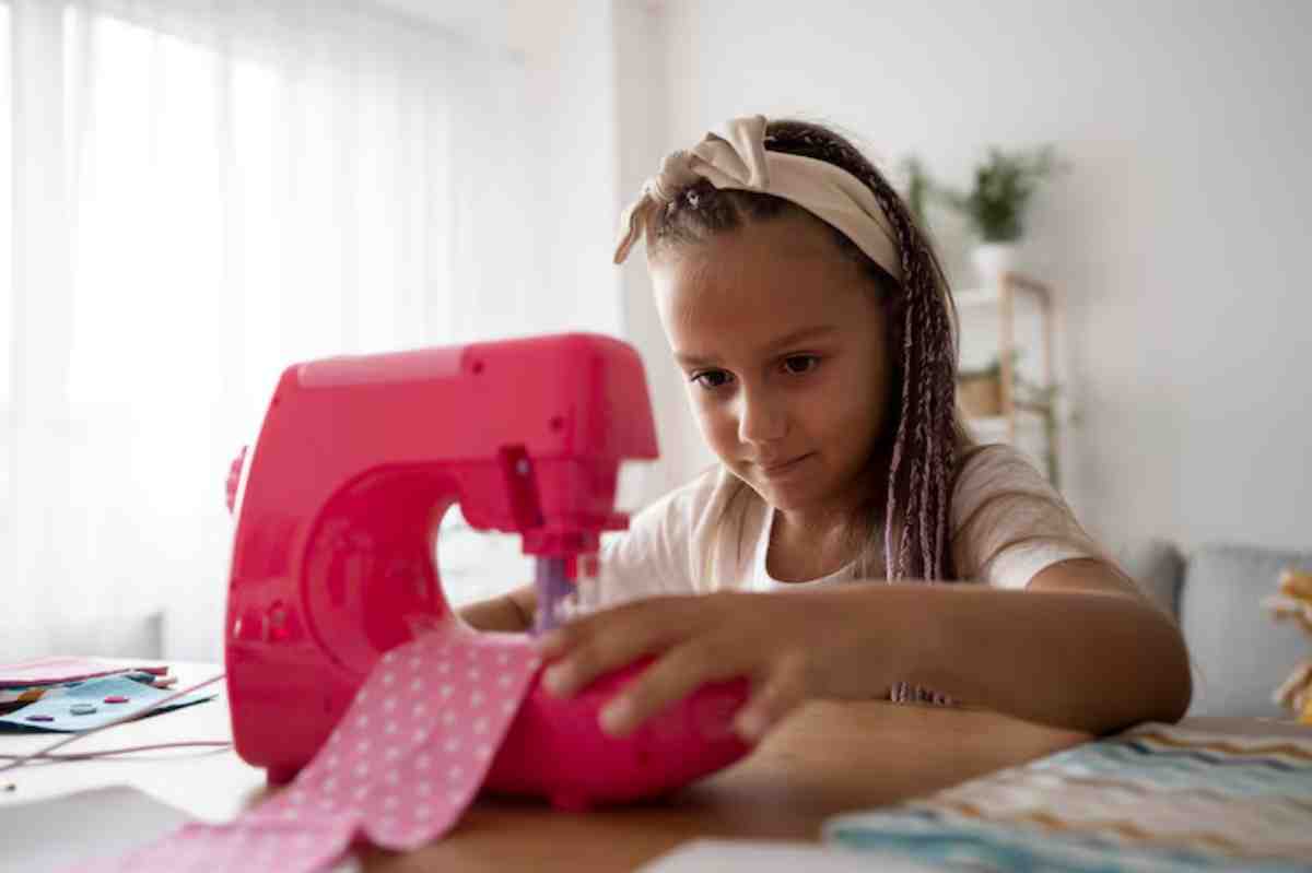 A person operates a bright pink sewing machine, working with polka-dotted fabric on a wooden table in a well-lit room.